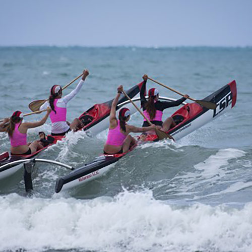 Women paddling the CSP Twin Hull Canoe through surf