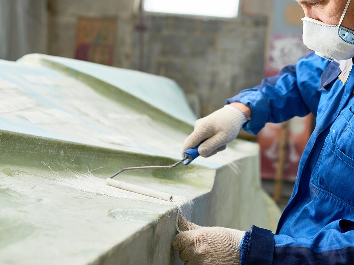 Man making fibreglass repairs on a boat body